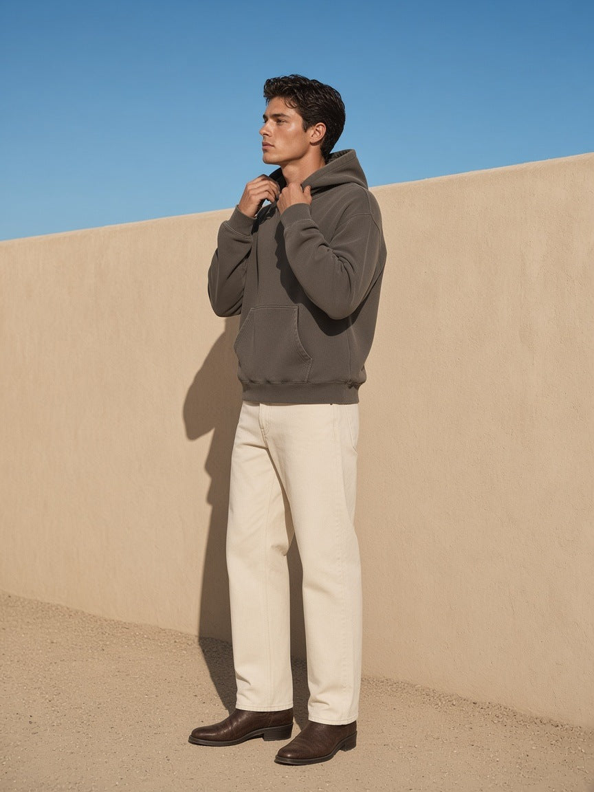 Man in the mineral wash boxy hoodie in Coffee standing against an adobe wall in Marfa, Texas in the morning
