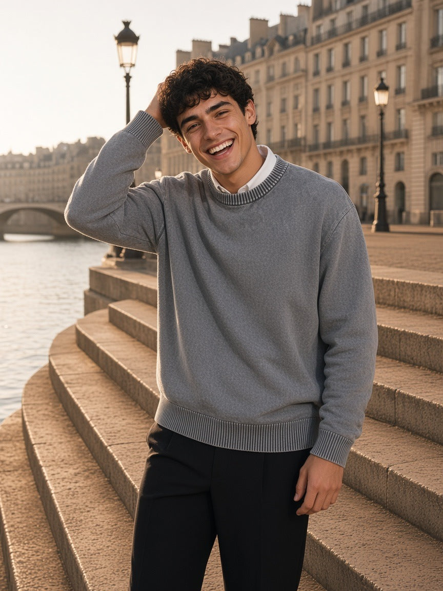 Man in the Mineral Wash Crewneck Sweater in Gray, laughing on the stone steps of a Seine quay in Paris in the morning