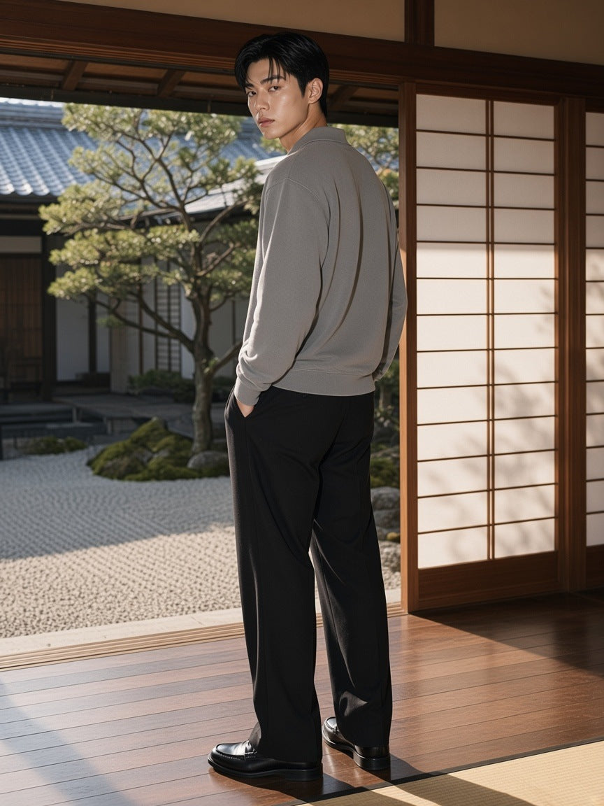 Man in the Mineral Wash Pullover Sweatshirt in Medium Gray with black pleated trousers and loafers, on a ryokan veranda in Kyoto in the morning