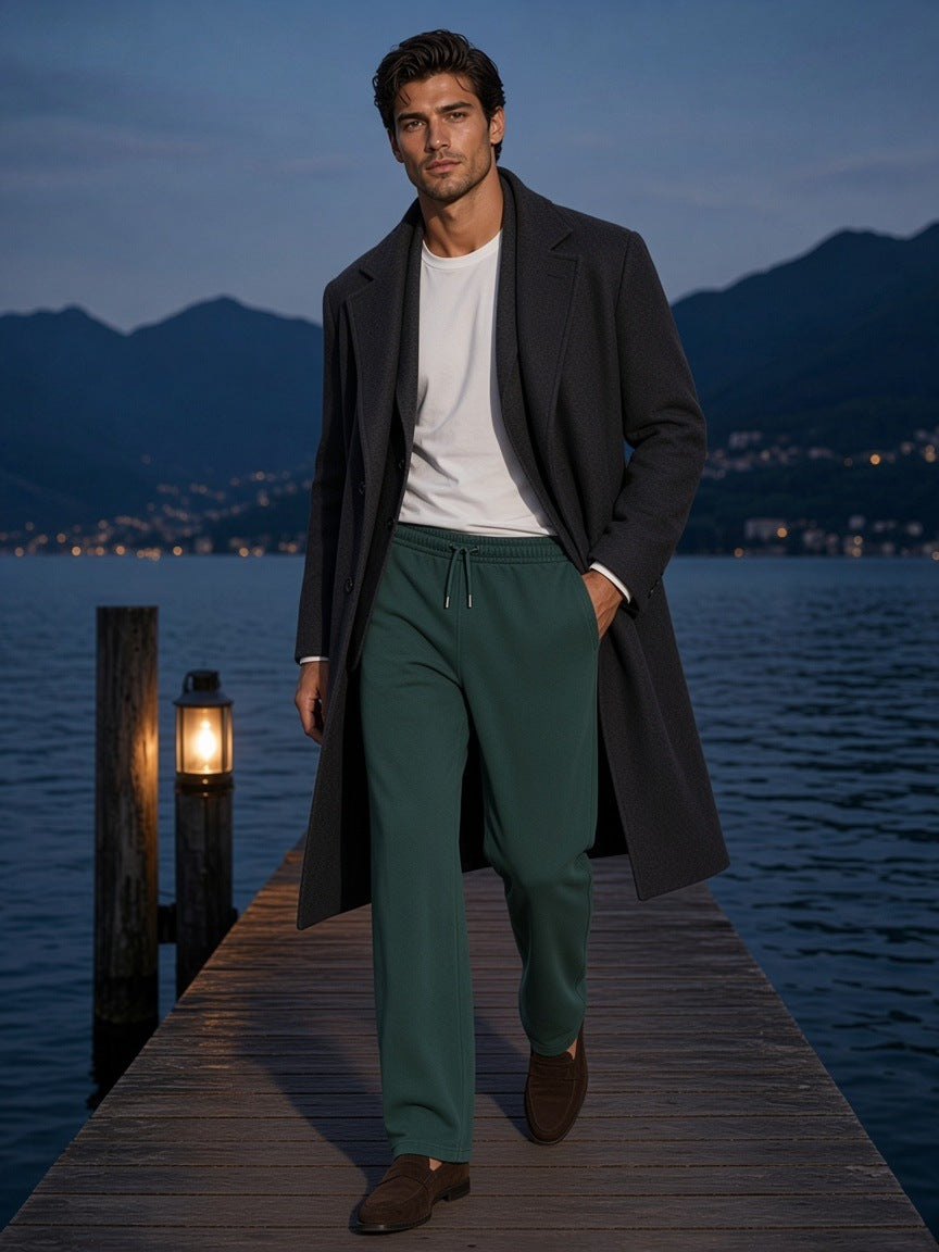 Man in the Mineral Wash Straight Sweatpants in Blackish Green walking a villa dock on Lake Como at blue hour