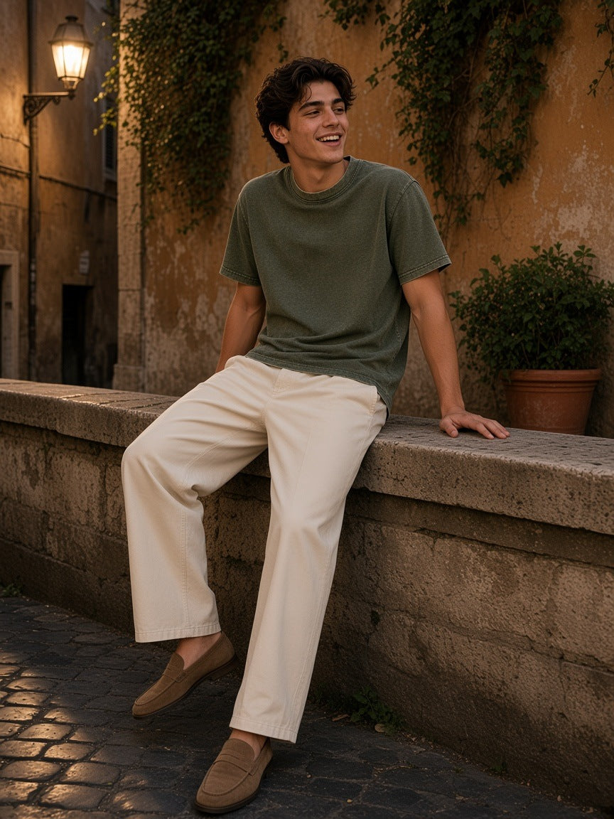 Man in the Marcel Afters Mineral Wash Waffle Knit T-Shirt in Army Green on a stone wall in a Rome side street at night