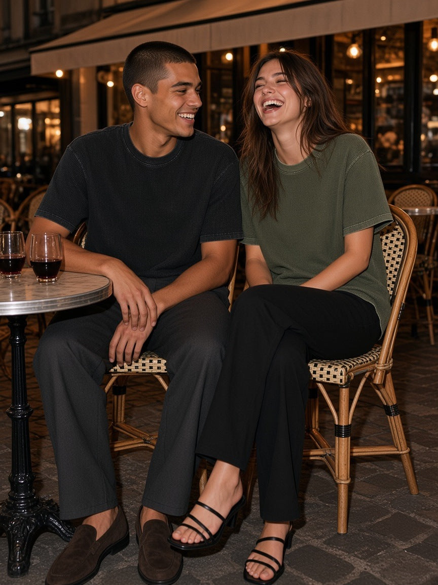 Two people in the Marcel Afters Mineral Wash Waffle Knit T-Shirt in Black and Army Green on a Paris café terrace at night