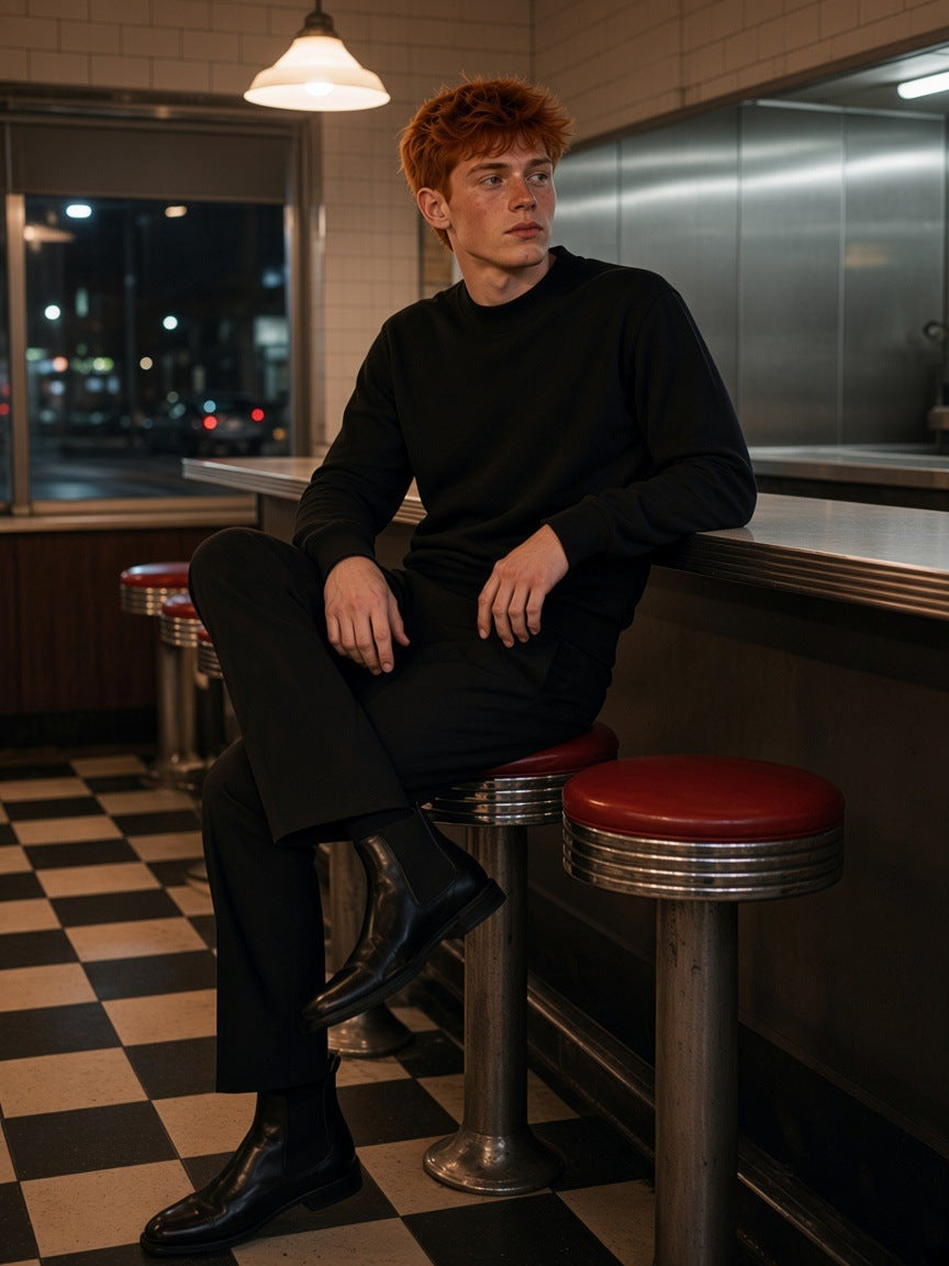 Man in the Mock Neck Sweatshirt in Black, on a counter stool in a Bowery diner in New York at night
