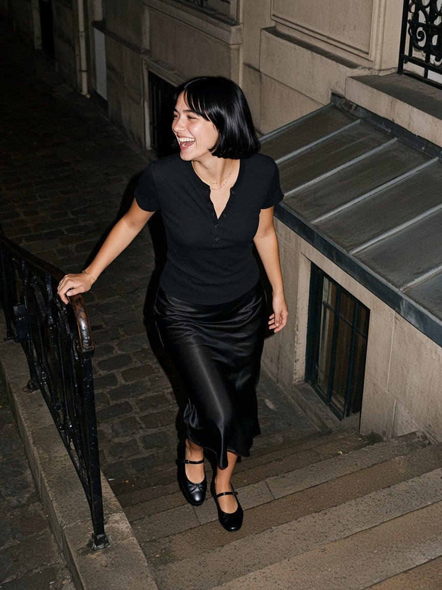 Woman in the Modal Bodycon Henley Shirt in Black with a satin skirt, climbing out of a Saint-Germain jazz cellar in Paris at 2am