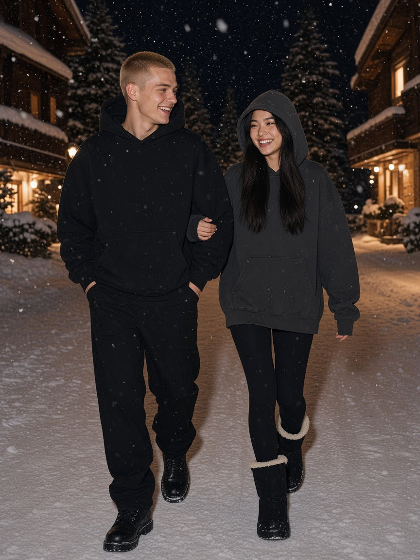 Two people in the Marcel Afters Oversize Heavyweight Fleece Hoodie in Black Beauty and Charcoal on a snowy St Moritz lane at night