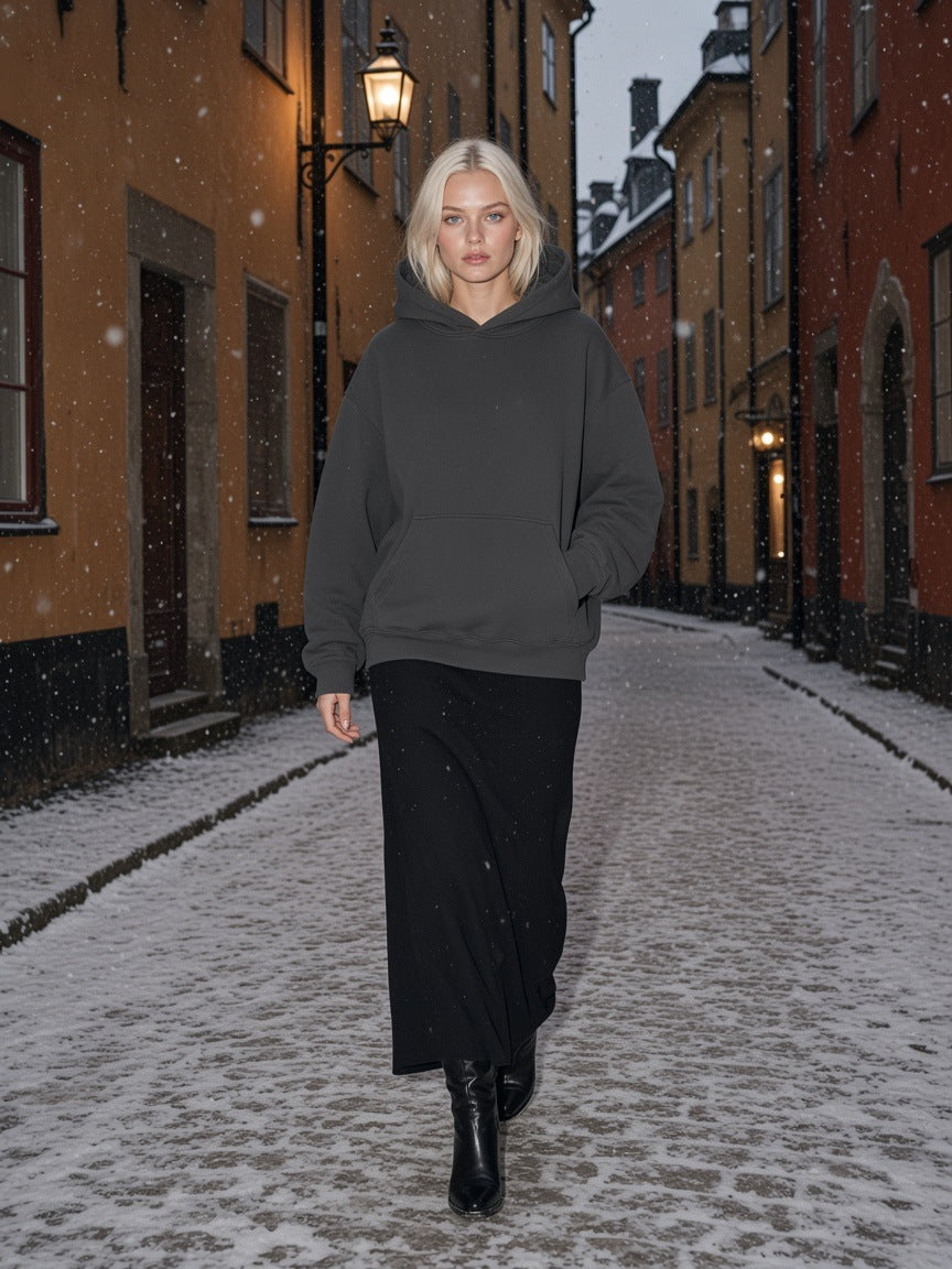 Woman in the Marcel Afters Oversize Heavyweight Fleece Hoodie in Charcoal on a snowy lane in Gamla Stan, Stockholm at night
