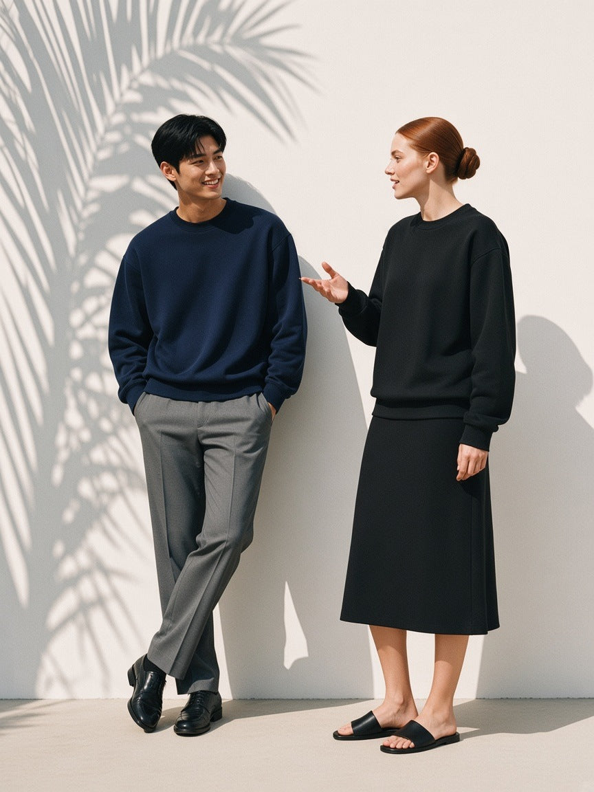 Two people in the Oversized Drop Shoulder Crewneck Sweatshirt in Navy Blue and Black against a white plaster wall with palm shadow by day