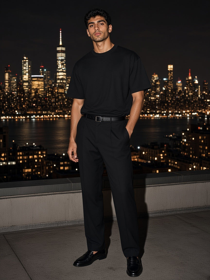 Man in the Marcel Afters Oversized Drop Shoulder T-Shirt in Black on a rooftop over the Hudson in New York at night