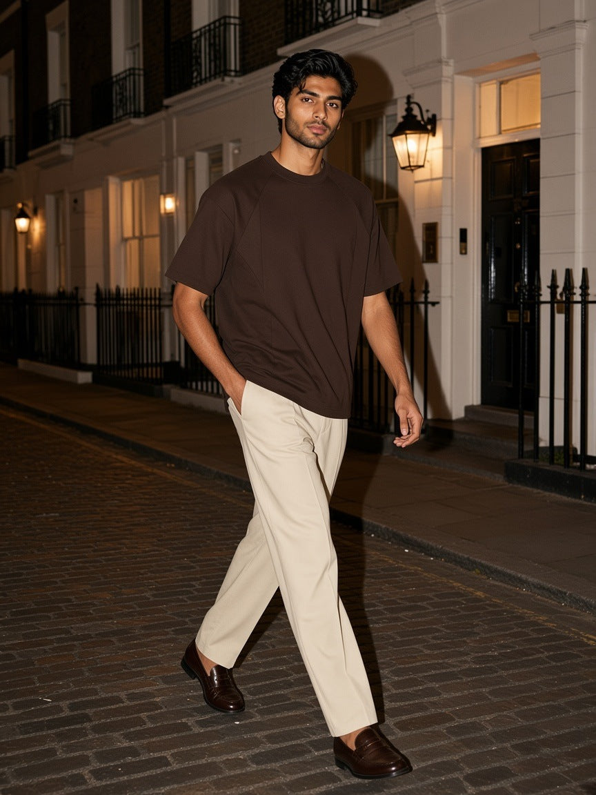 Man in the Oversized Paneled Raglan T-Shirt in Brown walking a cobbled mews in Mayfair, London at night
