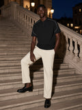 Man in the Oversized Piping Henley T-Shirt in Black on a travertine palazzo stair in Milan at night