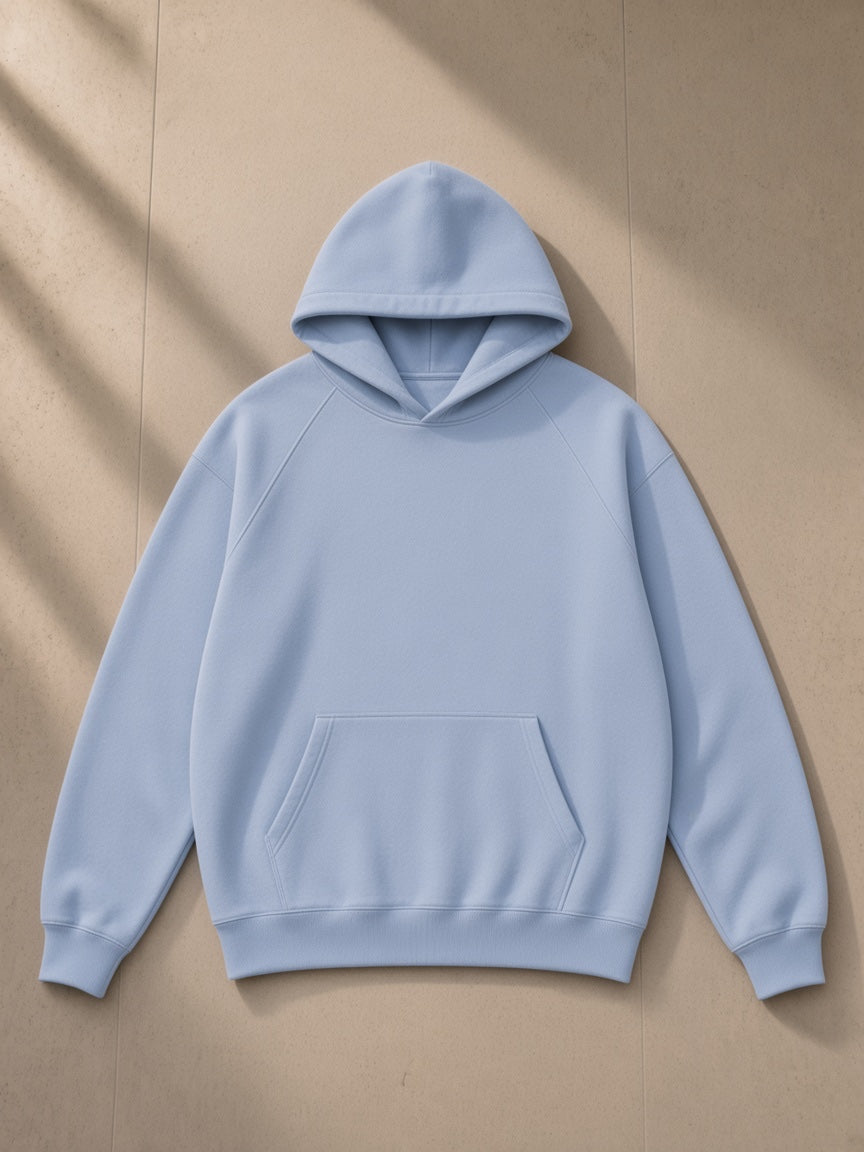 Oversized Raglan Pullover Hoodie in Light Blue, laid flat on pale limestone, front view