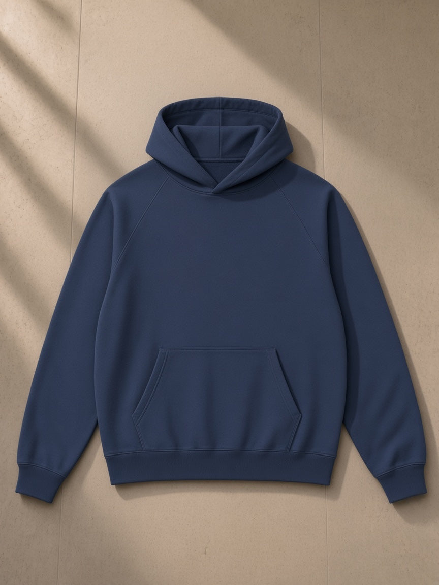 Oversized Raglan Pullover Hoodie in Navy Blue, laid flat on pale limestone, front view