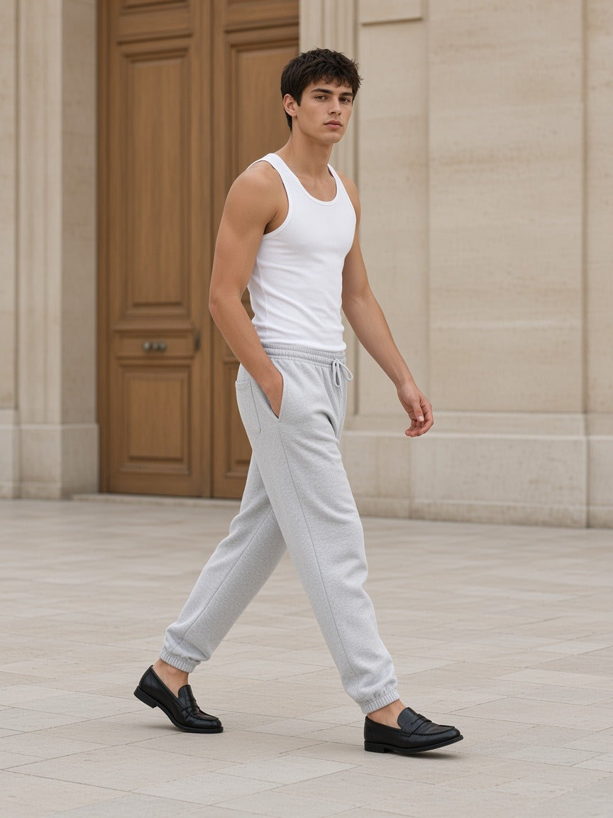 Man in the Marcel Afters Men's Heavyweight Fleece Joggers in Flower Gray walking across a pale limestone Paris courtyard in soft daylight