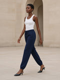 Woman in the Women's Loose Fit Tapered Joggers in Navy Blue striding across a limestone Paris courtyard in slingback heels