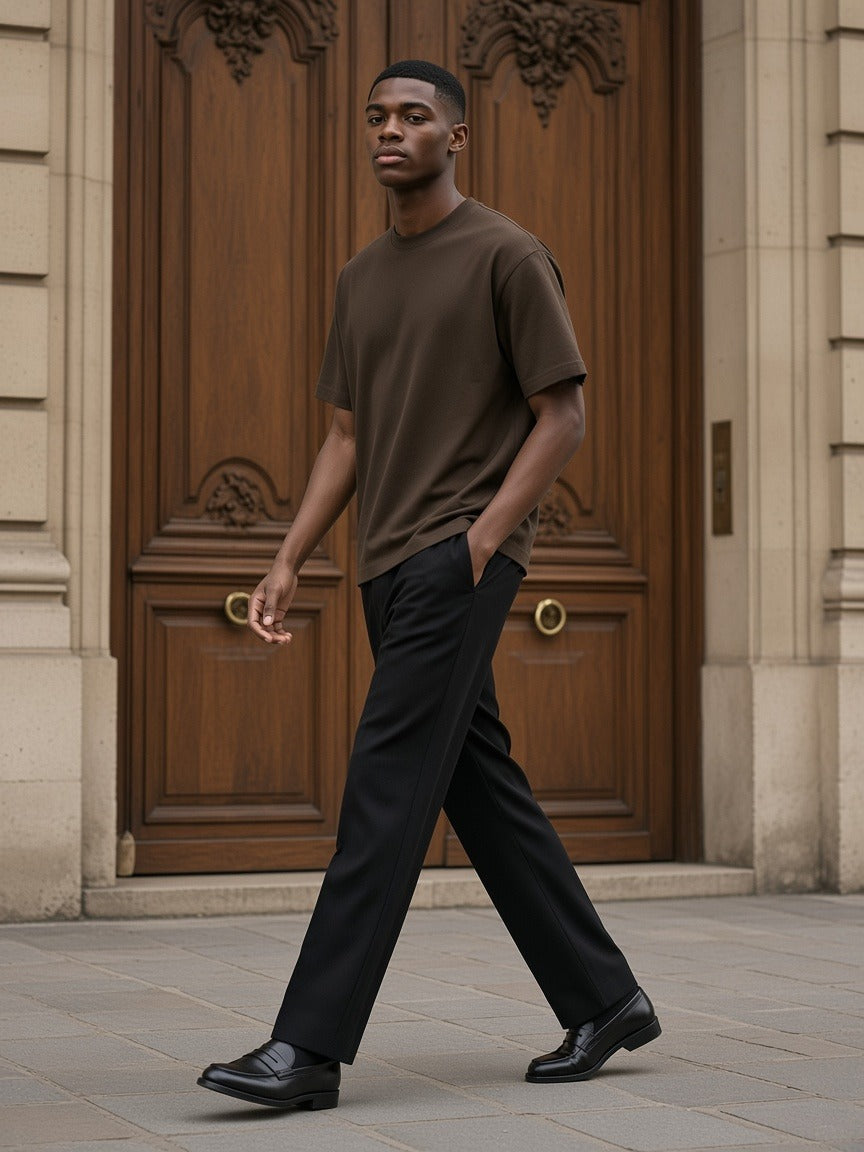 Man in the Men's Heavyweight Boxy T-Shirt in Coffee walking past a Haussmann doorway in soft daylight