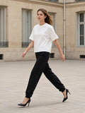 Woman in the Women's Heavyweight Boxy T-Shirt in White striding across a limestone Paris courtyard in black heels
