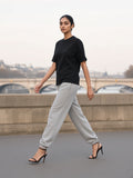 Woman in the Women's Boxy Oversized T-Shirt in Black striding along an empty Seine quai at dawn in strappy heels