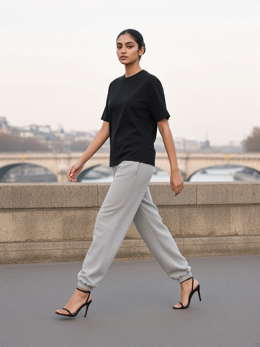 Woman in the Women's Boxy Oversized T-Shirt in Black striding along an empty Seine quai at dawn in strappy heels