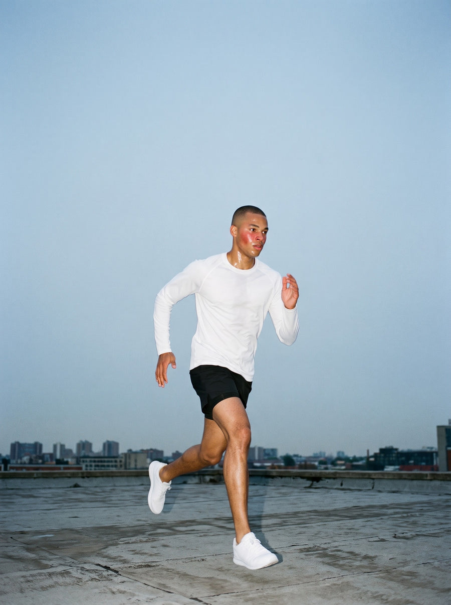 Man in the Performance Long Sleeve T-Shirt in White, running across a rooftop before sunrise