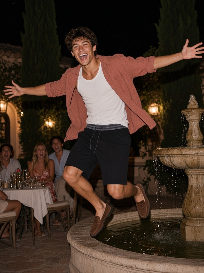 Man in the Plaid Waistband Shorts in Black walking a villa garden path on the Côte d'Azur at night