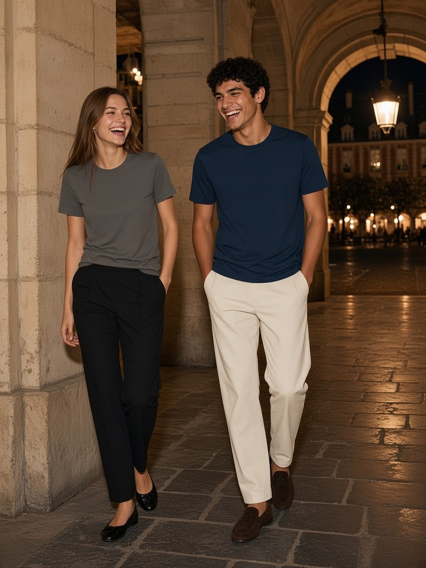 Two people in the Marcel Afters Pure Cotton T-Shirt, 180 gsm in Charcoal Gray and Dark Blue under the Place des Vosges arcades at night