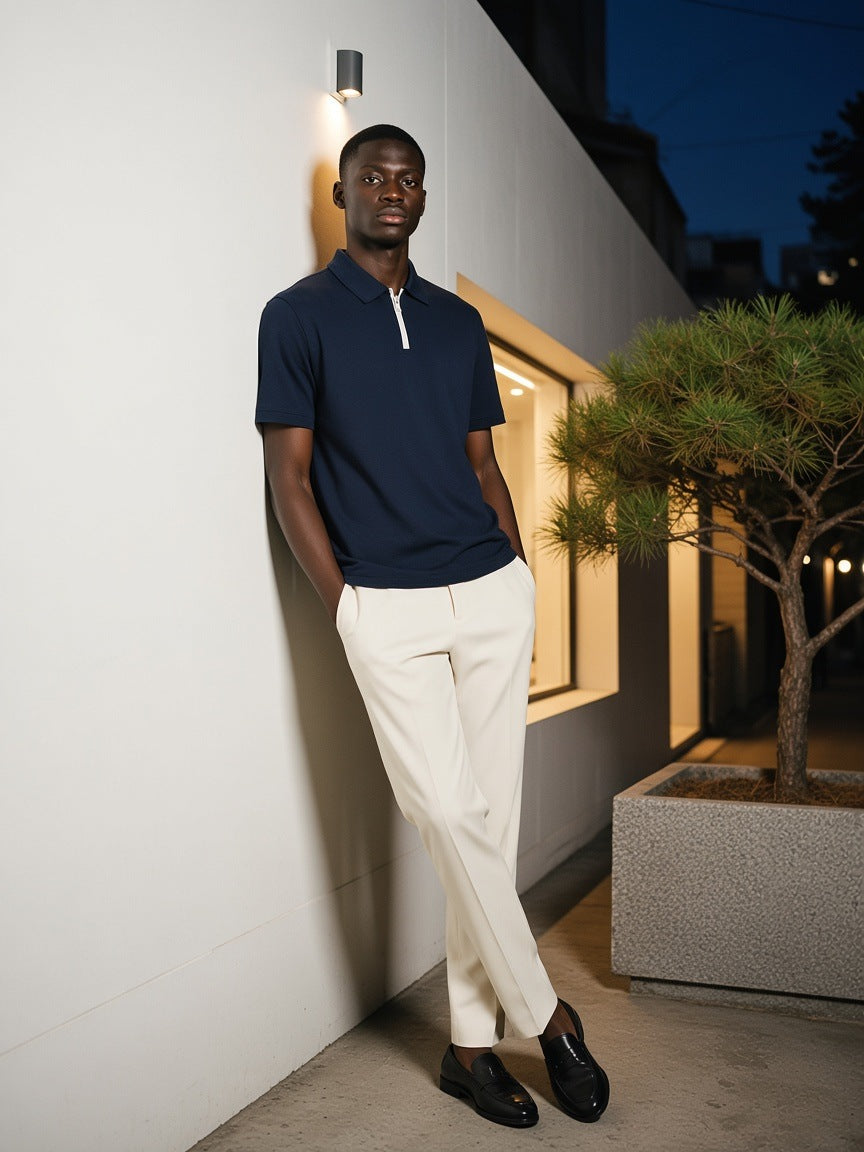 Man in the Quarter-Zip Knit Polo in Navy Blue, leaning on a white gallery wall in Hannam-dong, Seoul at night