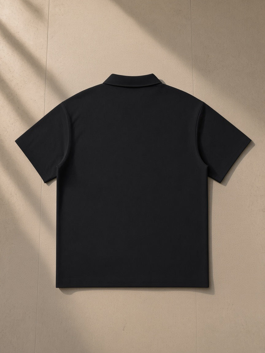 Quarter-Zip Polo Shirt in Black, laid flat on pale limestone, back view