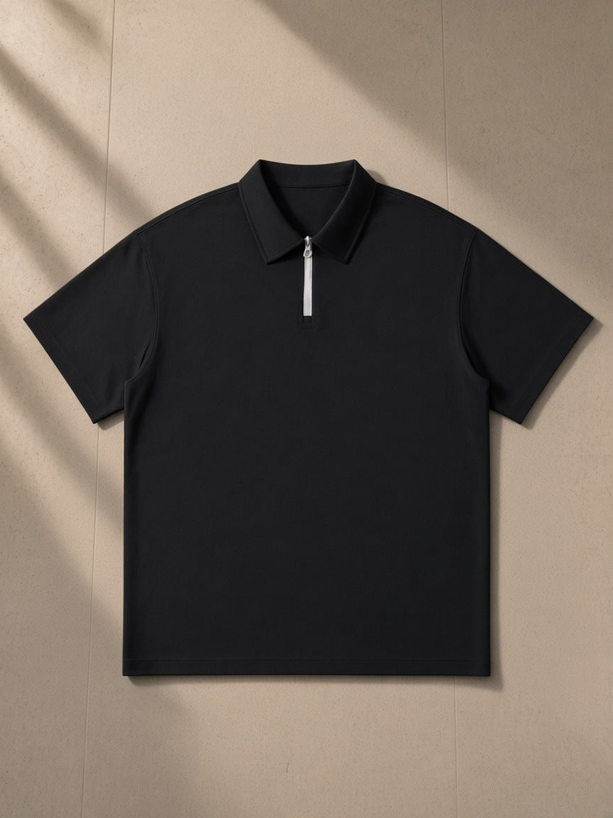 Quarter-Zip Polo Shirt in Black, laid flat on pale limestone
