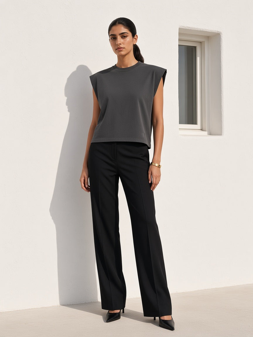 Woman in the Marcel Afters Raw Edge Boxy Sleeveless Top in Dark Gray, against a whitewashed wall in Mykonos