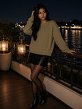 Woman in the Raw Edge Crewneck Sweatshirt in Khaki Green at a lantern-lit riverside terrace in Bangkok at night