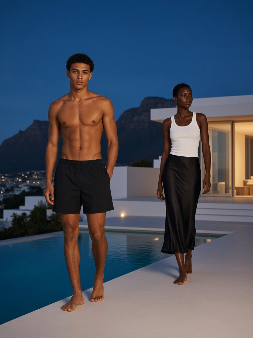 Two people in the Marcel Afters Regular Fit Shorts in Black, at a villa pool at blue hour in Cape Town