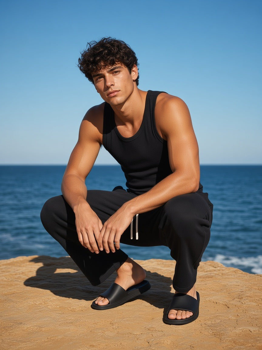Man in the Relaxed Drawstring Three-quarter Sweatpants in Black on sandstone above the sea in Sydney in the morning