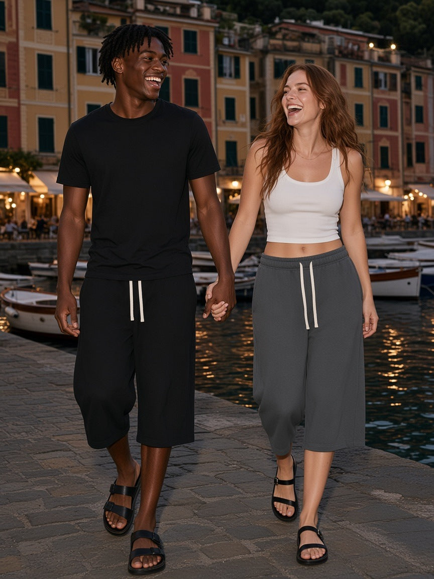 Two people in the Marcel Afters Relaxed Drawstring Three-quarter Sweatpants in Black and Charcoal Gray on the Portofino harbour at night