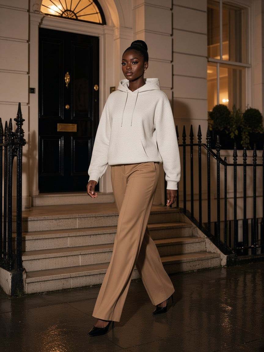 Woman in the Marcel Afters Relaxed Fit Hoodie in Oat Gray with camel trousers and heels, on Georgian steps in London at night
