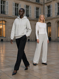 Two people in a limestone hotel courtyard in Paris at blue hour, one wearing the Relaxed Fit Hoodie in Flower Gray with black trousers and heels