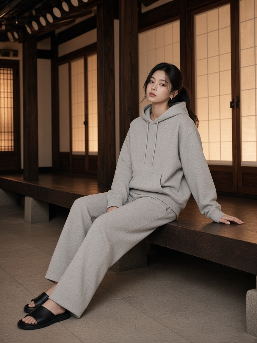 Woman in the Relaxed Pullover Hoodie in Flower Gray with grey wide sweatpants, in a Hanok courtyard in Seoul at night