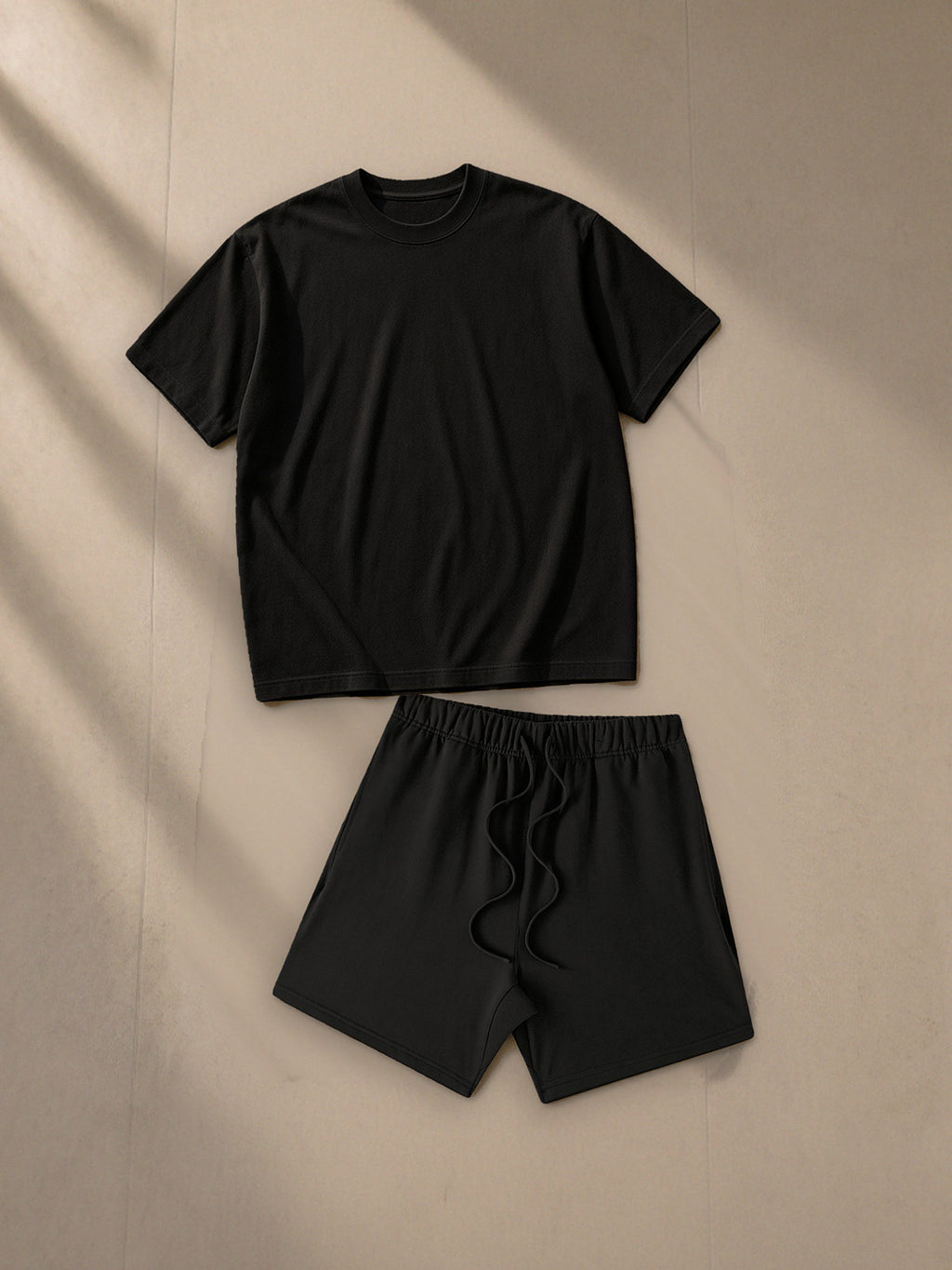 Women's Heavyweight Earth Tone T-Shirt + Earth Tone Loose Fit Cotton Shorts Set in Black, top and bottom laid flat together on pale limestone