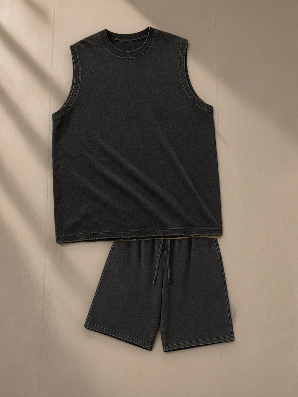 Men's Snow Washed Frayed Hem Tank Top + Snow Washed Raw Hem Shorts Set in Black, top and bottom laid flat together on pale limestone