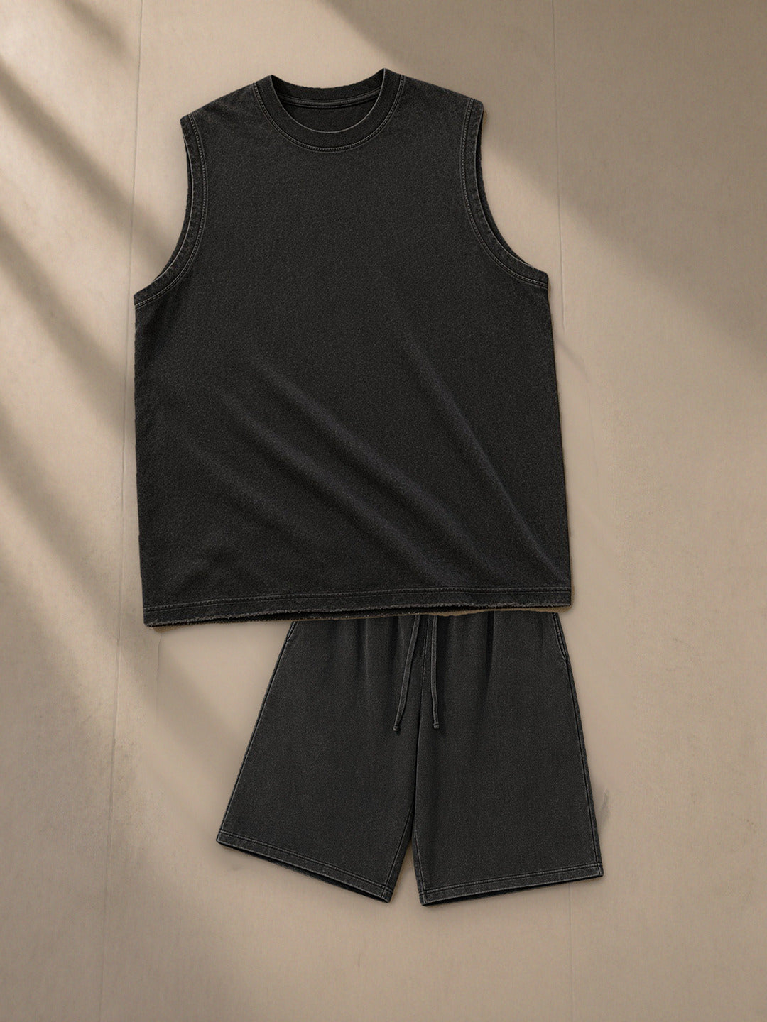 Men's Snow Washed Frayed Hem Tank Top + Snow Washed Raw Hem Shorts Set in Black, top and bottom laid flat together on pale limestone