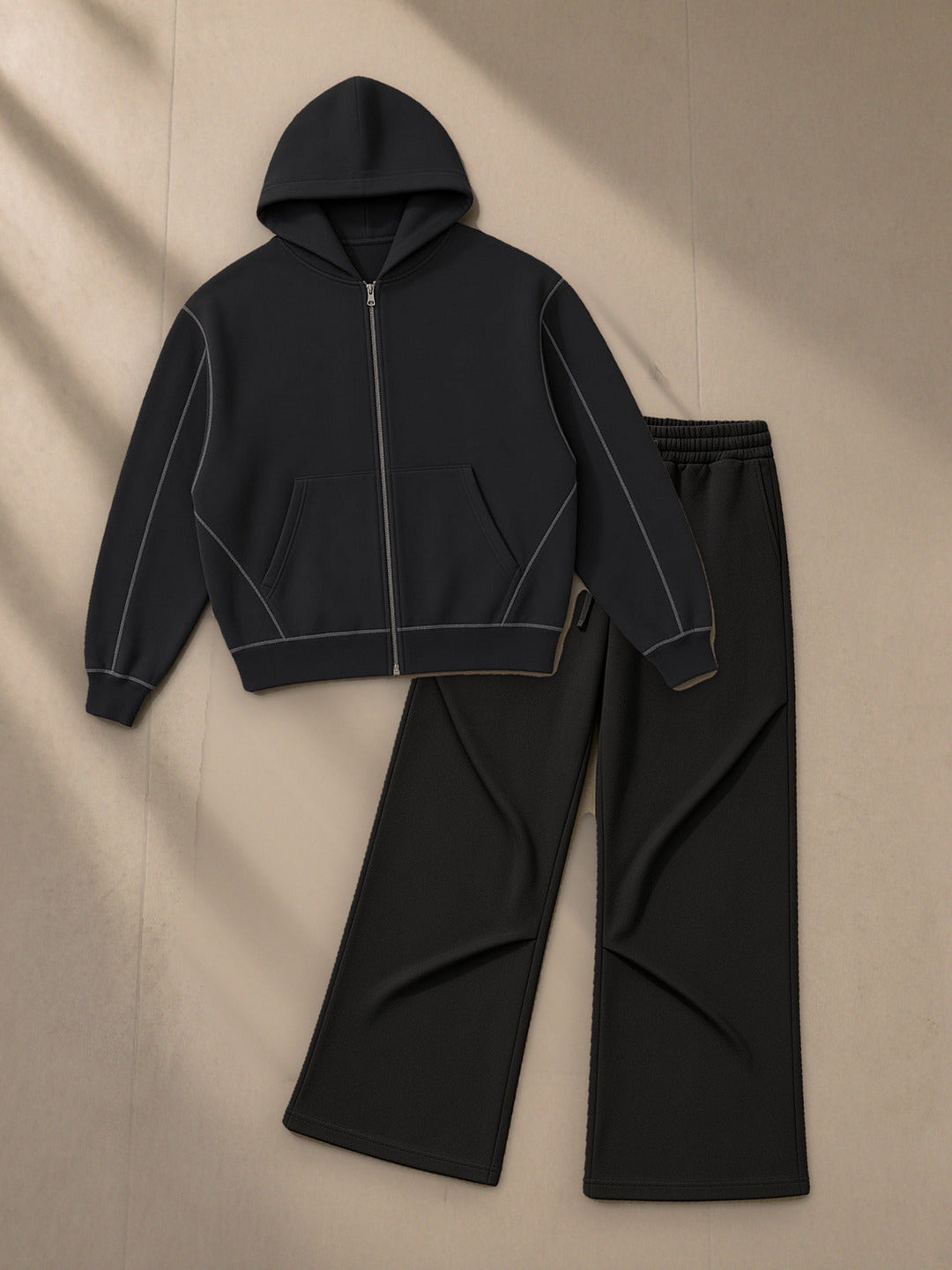 Contrast-Stitched Boxy Fleece Zip Hoodie + Wide Leg Drawstring Sweatpants Set in Black, top and bottom laid flat together on pale limestone