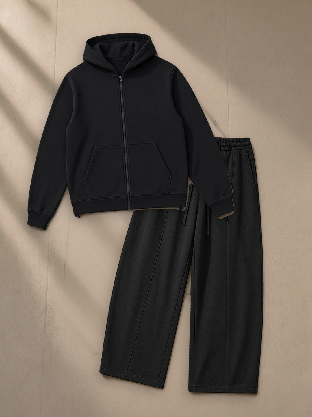 Paneled Full Zip Hoodie + Heavyweight Wide Leg Panel Sweatpants Set in Black, top and bottom laid flat together on pale limestone