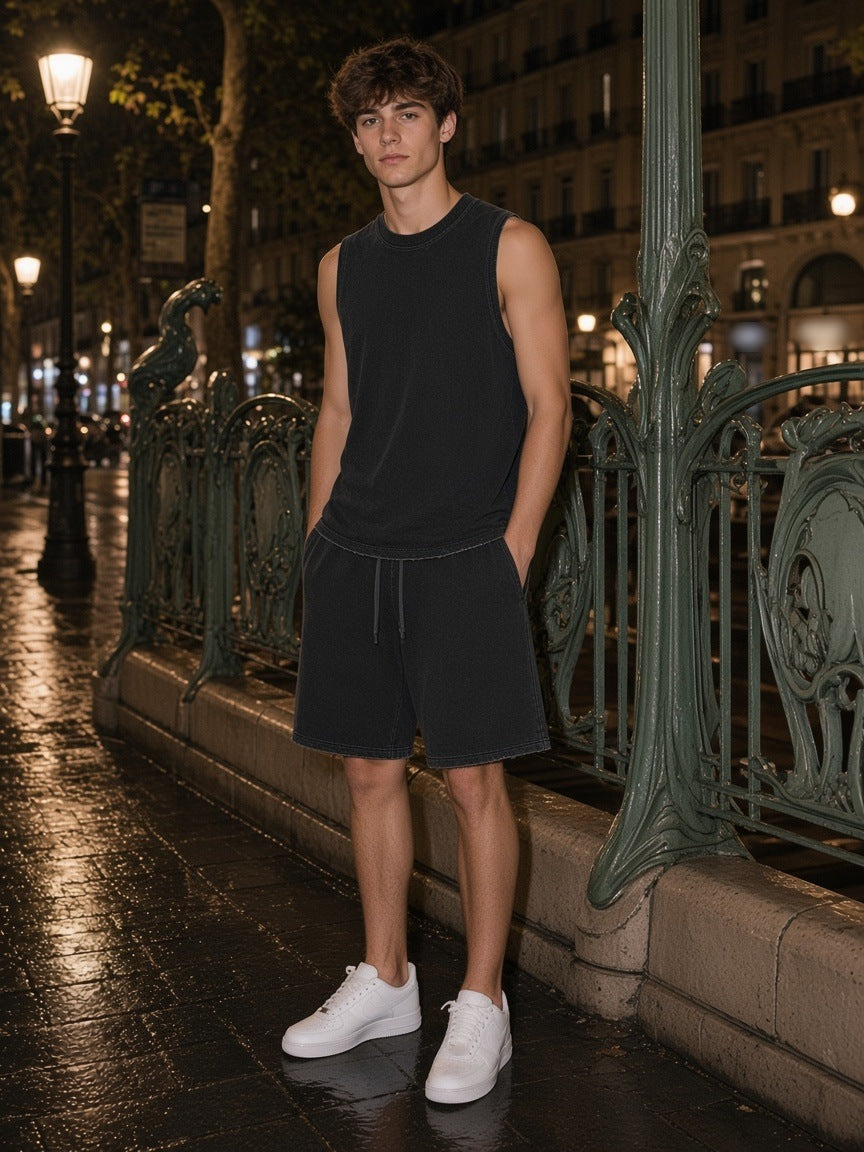 Man in the Black Snow Wash set, frayed hem tank and raw hem shorts, by a Paris metro railing at night