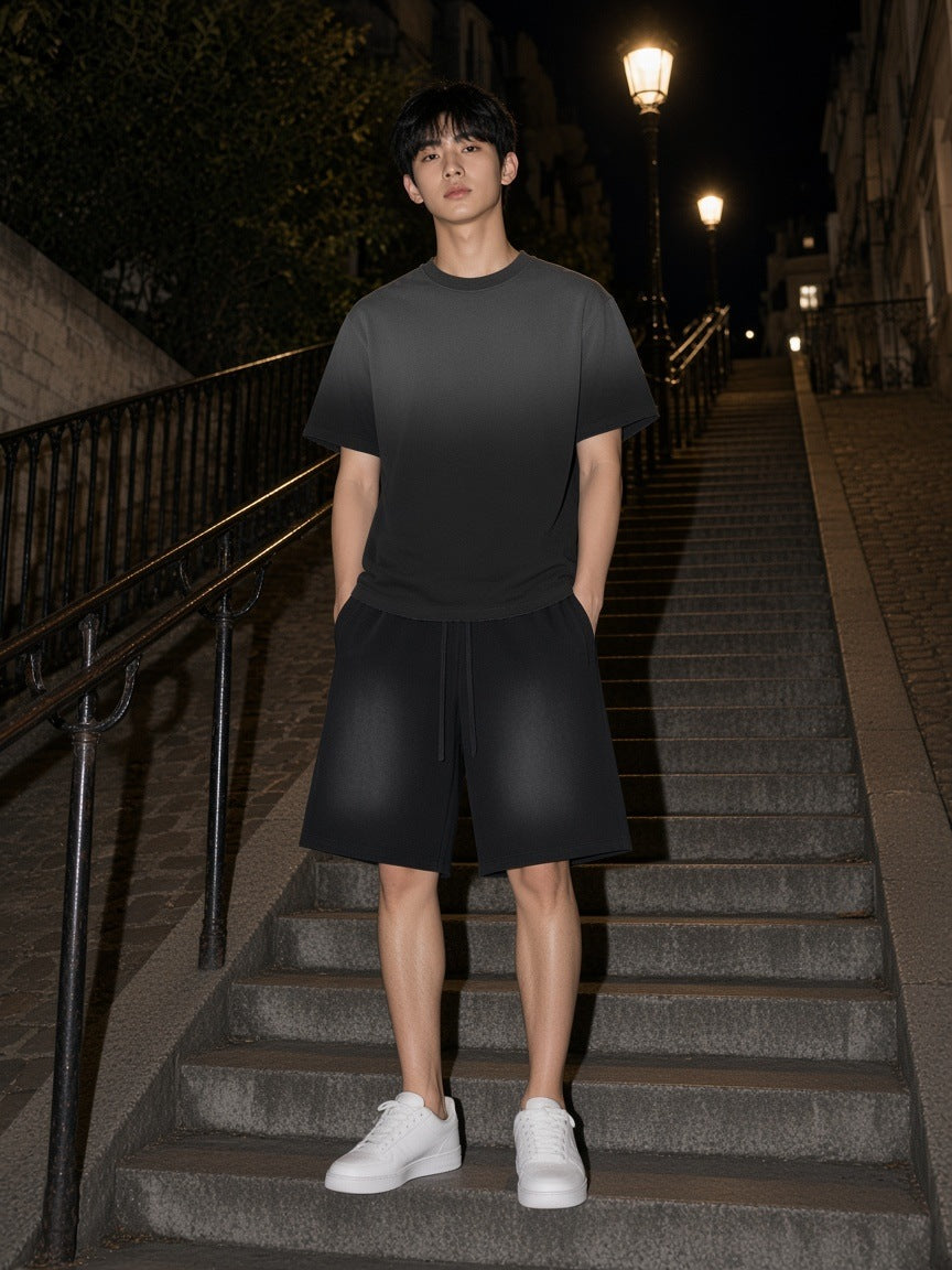 Man in the Black Sunfade set, raw edge tee and raw edge shorts, on the Montmartre stairs at night