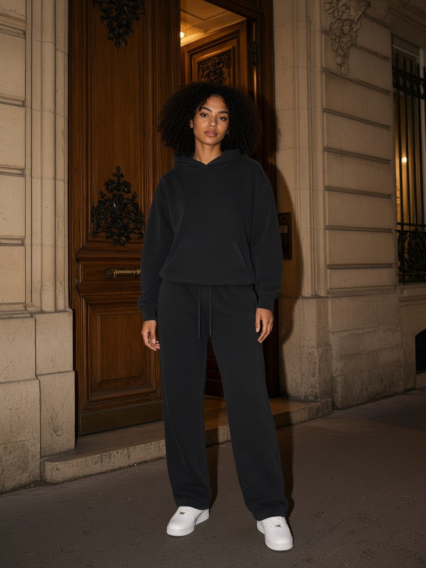 Woman in the Black Vintage Wash set, boxy hoodie and sweatpants, in a Haussmann doorway at night