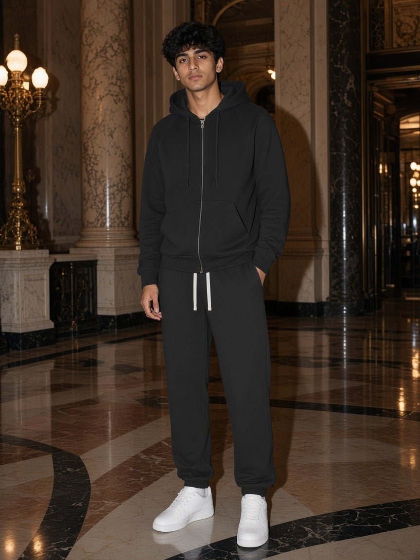 Man in the Black Fleece set, zip-up hoodie and fleece sweatpants, in a Paris hotel lobby at night