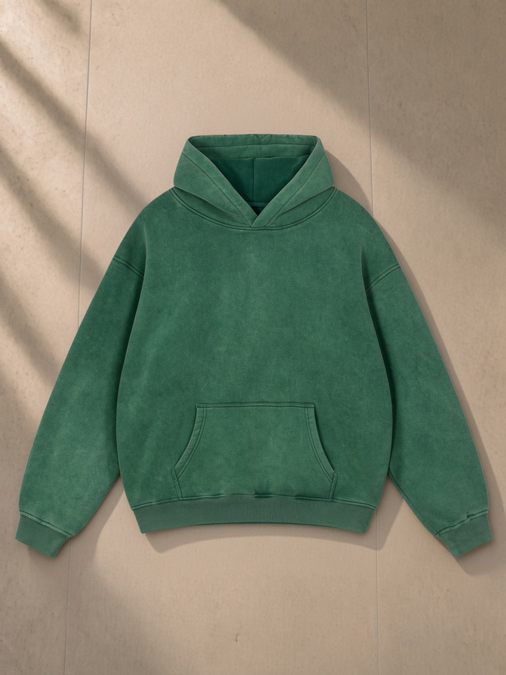 Snow Wash Fleece Oversize Hoodie in Dark Green, laid flat on pale limestone, front view