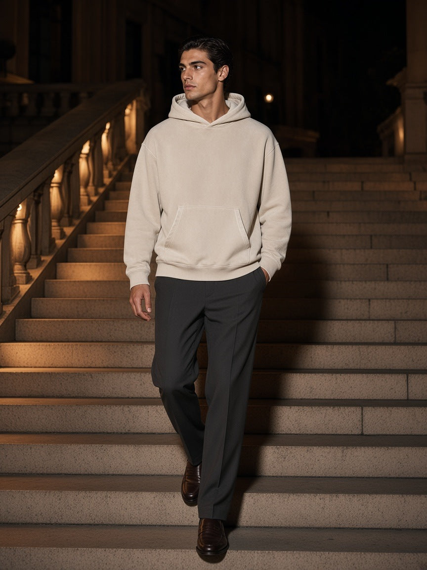 Man in the Marcel Afters Snow Wash Fleece Oversize Hoodie in Mild Apricot, on a stone stair in Milan