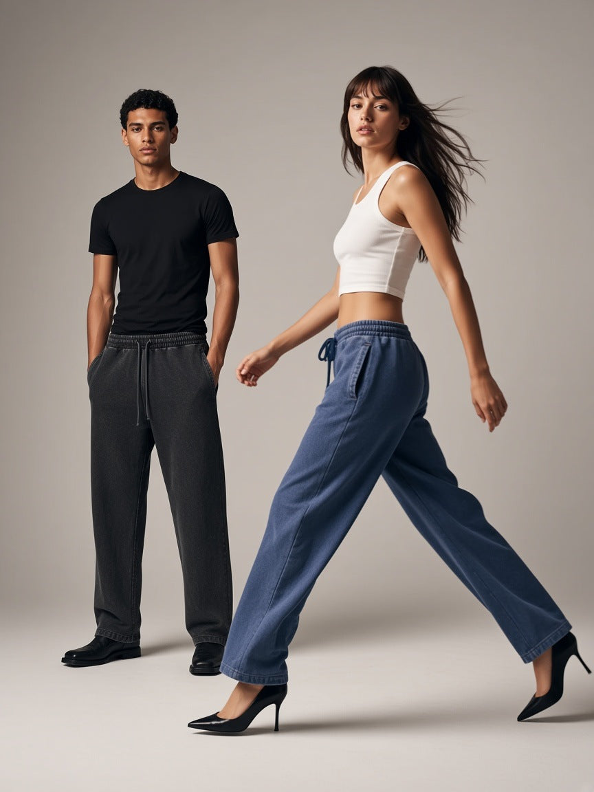Two people in the Marcel Afters Snow Wash Heavyweight Sweatpants in Black and Dark Blue, a woman striding in heels, a man standing still, stone studio
