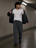 Man in the Snow Washed Raw Edge Sweatpants in Dark Gray with a white tee, leather jacket and lug-sole loafers, walking through a concrete tunnel exit in London at 2am