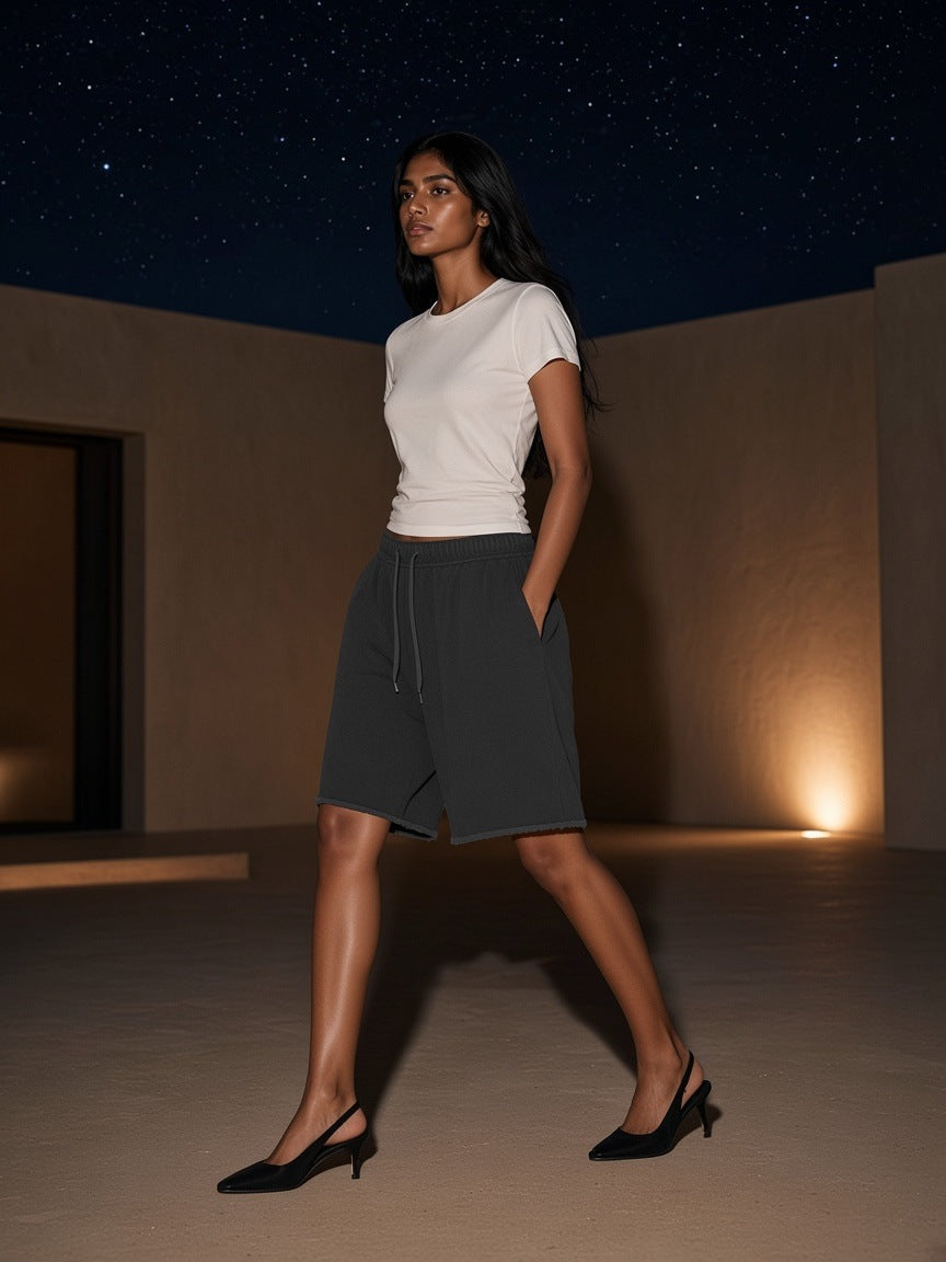 Woman in the Marcel Afters Snow Washed Raw Hem Shorts in Black crossing a desert resort courtyard at Amangiri at night